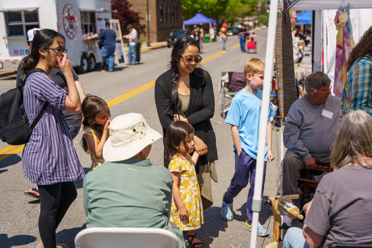 people watching a vendor spin yarn