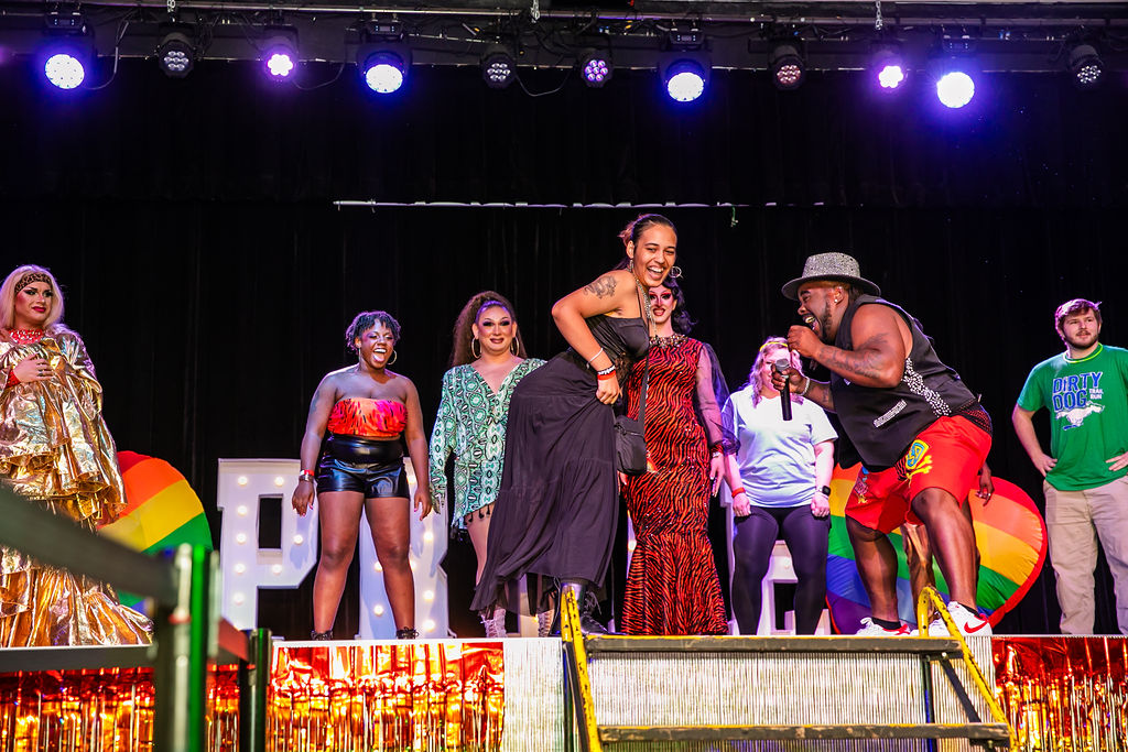 Pride After Party Drag Show host pulls attendee on stage in impromptu moment for attendee to perform.