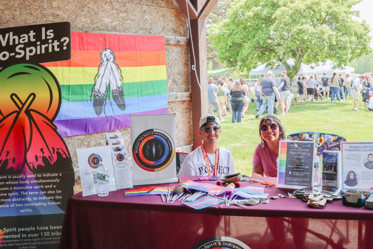 The Two Spirit & Indigiqueer Coalition tabling at Mount Pleasant Pride Festival with handouts, a two-spirit flag, and information/resources.