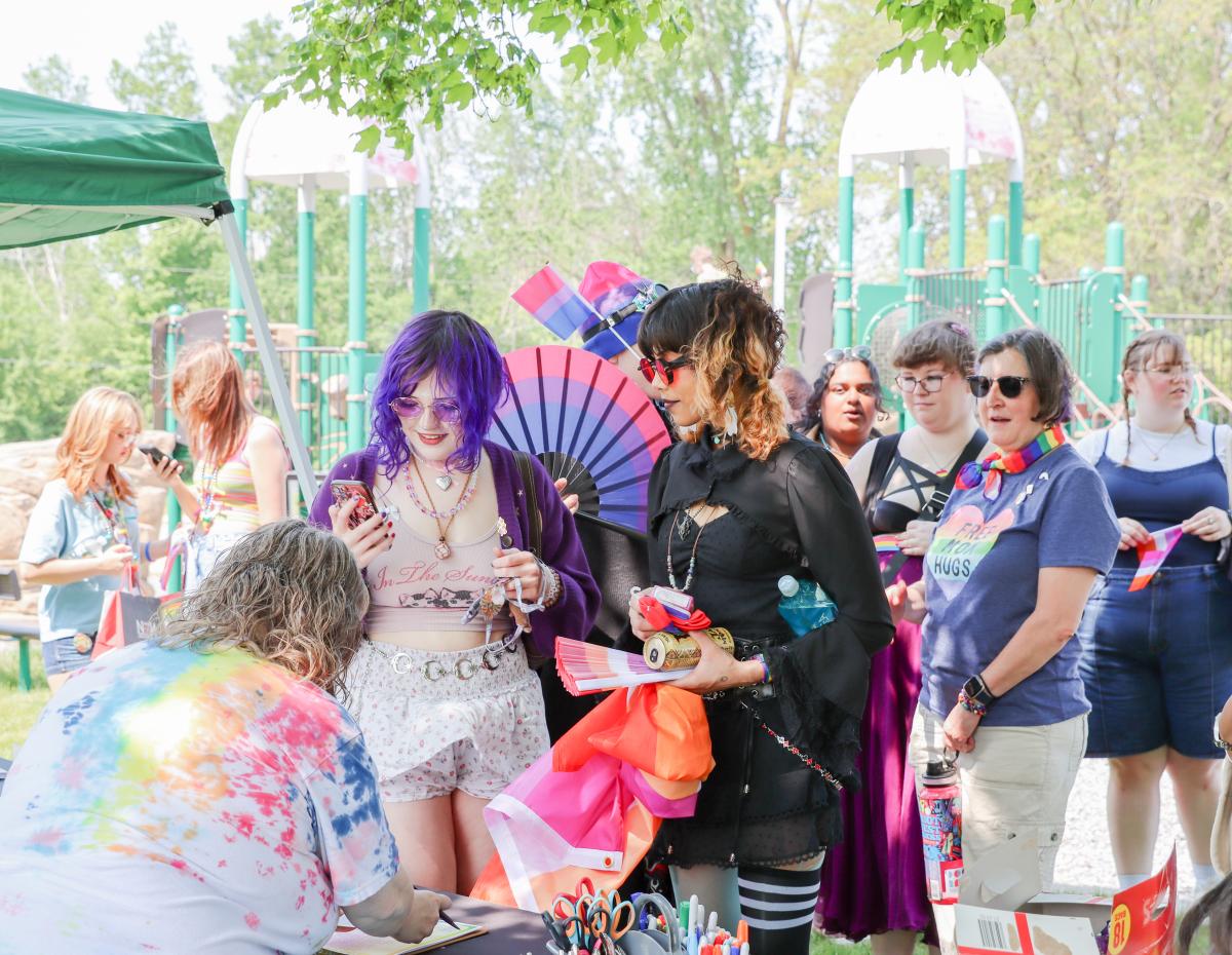 Two people at Mount Pleasant Pride Festival interacting with a vendor.