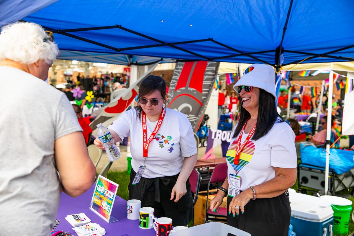 Two Great Lakes Bay Pride Festival volunteers handing out free water at the water tent.