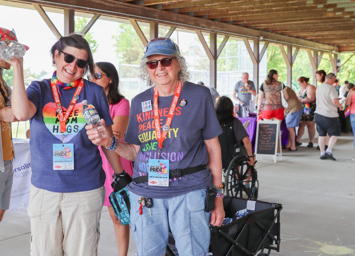 Two Mount Pleasant Pride Festival volunteers holding water bottles and smiling at the camera.
