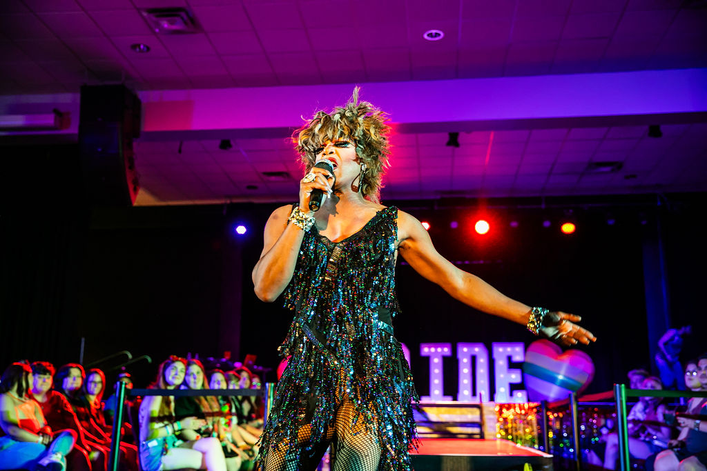 Pride After Party Drag Show drag performer performing a Tina Turner impersonation with a microphone among the crowd.