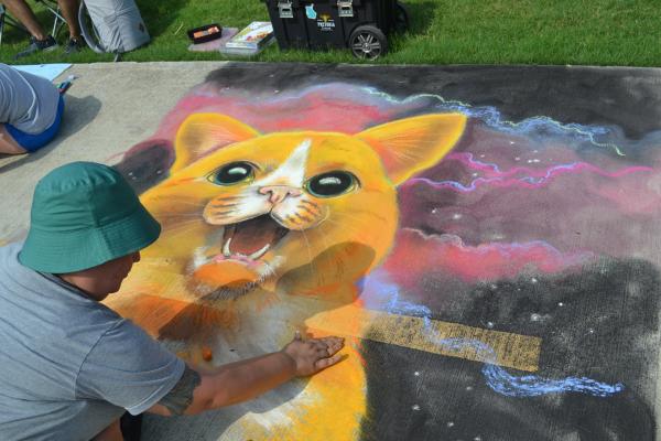 Professional Chalk Artist working on an orange cat portrait at the 2022 Chalk Walk