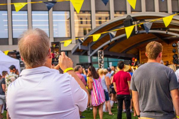 A man takes a photo of the band playing on the stage at Fargo Broadway Square.