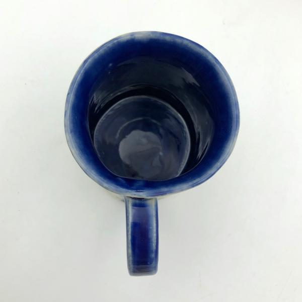 Handmade ceramic coffee mug with blurred blue flowers picture
