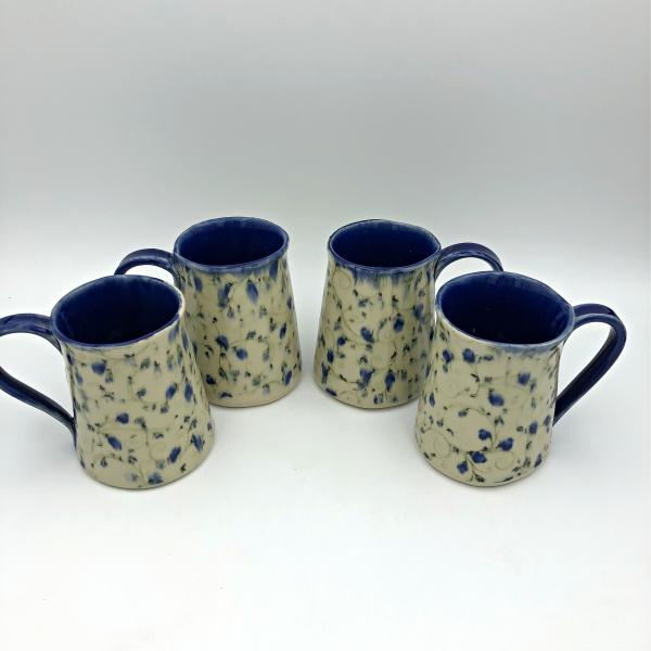 Handmade ceramic coffee mug with blurred blue flowers picture