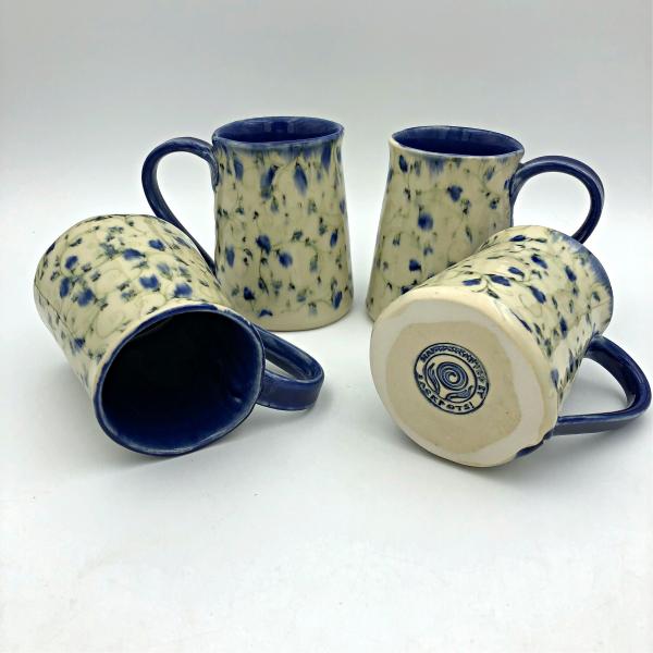 Handmade ceramic coffee mug with blurred blue flowers