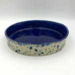 Handbuilt cake pan with rich cobalt glaze inside and blue floral pattern outside.