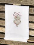A Christmas ornament is embroidered on a white flour sack tea towel, dish towel, cotton