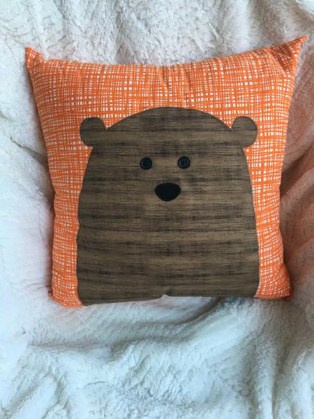 Brown bear appliqué on orange and white pillow