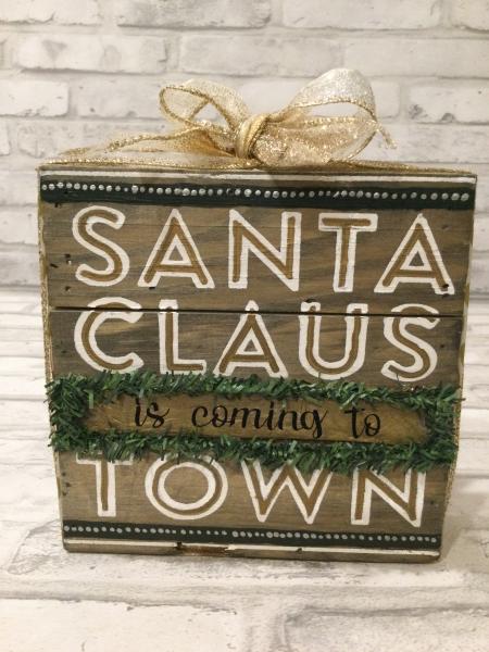 Wood sign with Santa Claus is coming to town.